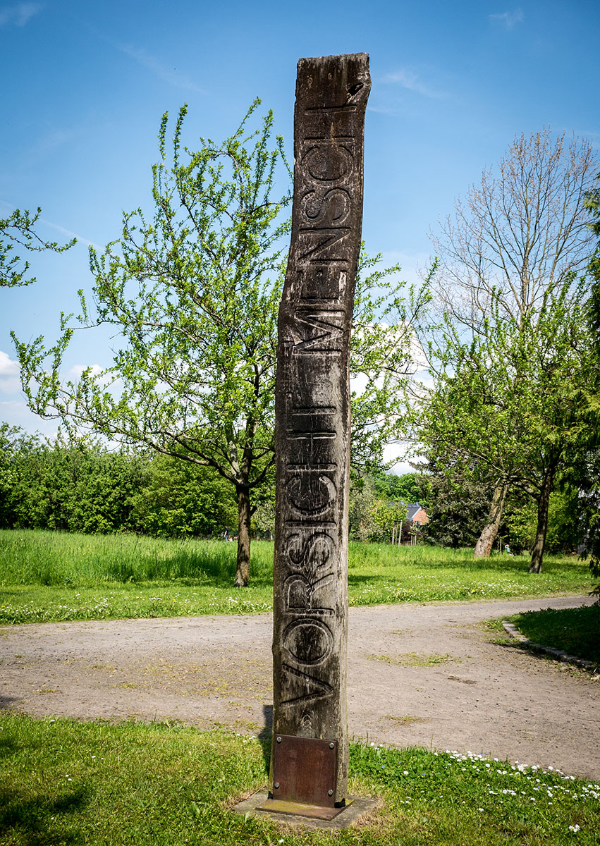 Kunstwerk: Holzsäule mit Inschrift